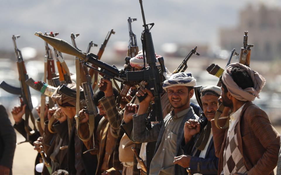 Newly-recruited members of the Houthis' popular army brandish weapons during a gathering at the end of a military training