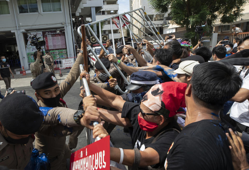 Anti-government protesters push a metal barrier into inside of the Samranrat police station in Bangkok, Thailand, Friday, Aug, 28, 2020. The protesters tussled with police in the Thai capital on Friday as 15 of their movement leaders turned up at a police station to answer a summons linked to demonstrations denouncing the arrests. (AP Photo/Sakchai Lalit)