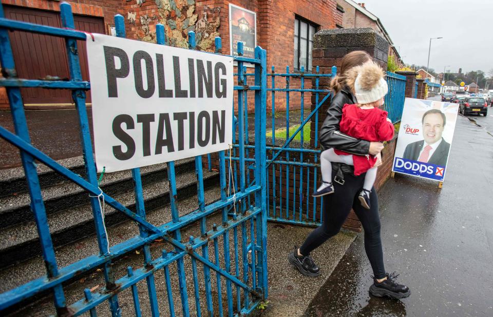 A voter passes an advertising board featuring an image of the Democratic Unionist Party's (DUP) deputy leader Nigel Dodds, as she leaves from a polling station in Belfast, Northern Ireland, as Britain holds a general election on December 12, 2019. (Photo by Paul Faith / AFP) (Photo by PAUL FAITH/AFP via Getty Images)