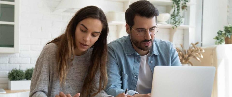 Serious man and woman calculating bills, using calculator and laptop, online banking services, family discussing and planning budget, focused wife and husband checking finances together