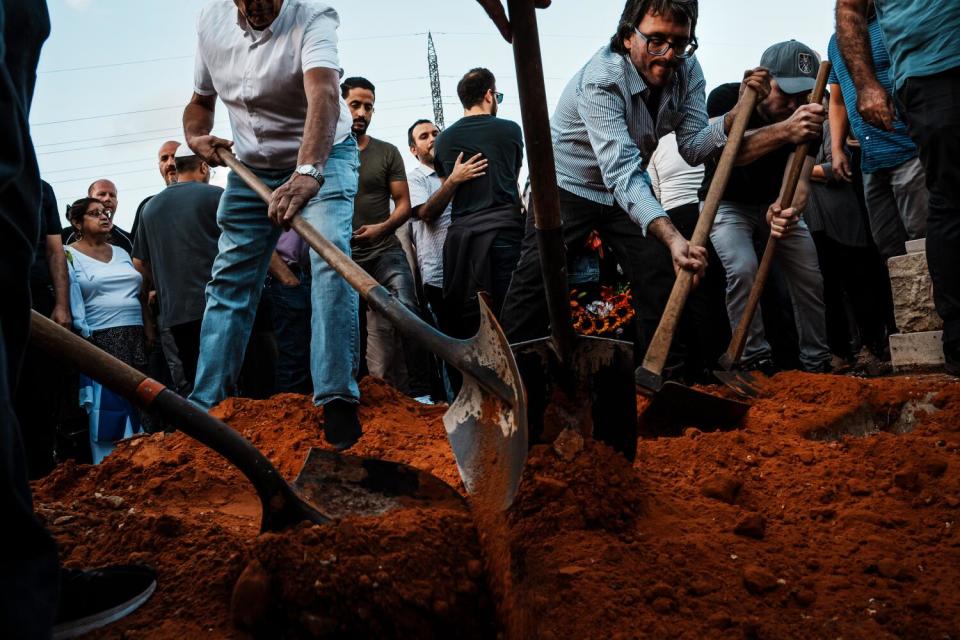 Michael Levy, center right, joins others to help bury his brother Daniel Levy.