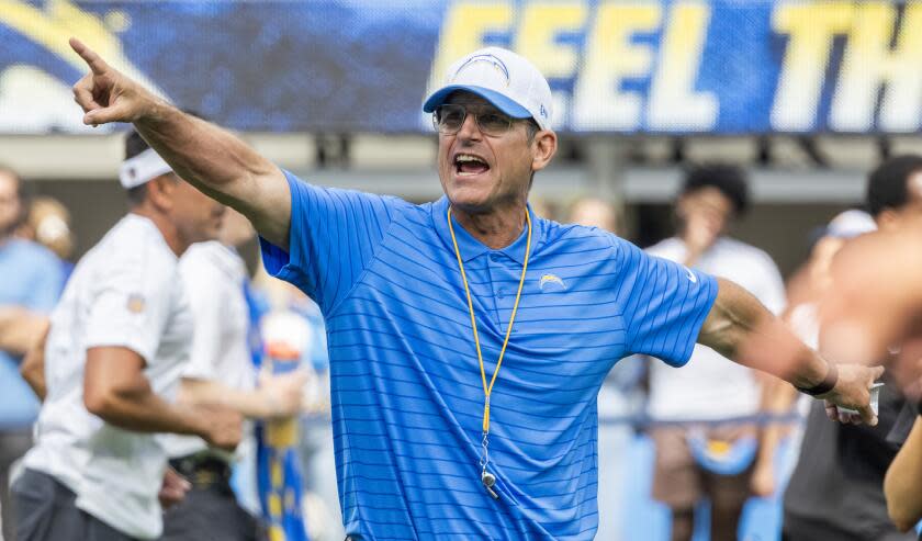 Coach Jim Harbaugh waves to his Chargers from the sidelines.