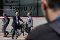 People wait for traffic lights in front of an electronic stock board showing Japan's Nikkei 225 index at a securities firm Wednesday, May 22, 2024, in Tokyo. (AP Photo/Eugene Hoshiko)