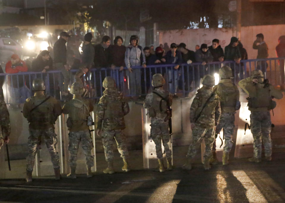 Lebanese army soldiers deploy on a highway that links to the airport, which was blocked by anti-government protesters, background, during a protest against the new government, in Beirut, Lebanon, Tuesday, Jan. 21, 2020. Lebanon's prime minister designate Hassan Diab announced Tuesday a new government for the crisis-hit country, breaking a months-long impasse amid ongoing mass protests against the country's ruling elite. (AP Photo/Hussein Malla)