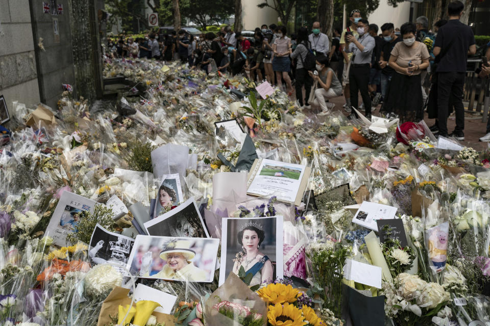 Flowers, messages and photographs are placed for Queen Elizabeth II outside the British Consulate in Hong Kong, Friday, Sept. 16, 2022. In Britain, Thousands of mourners waited for hours Thursday in a line that stretched for almost 5 miles (8 kilometers) across London for the chance to spend a few minutes filing past Queen Elizabeth II's coffin while she lies in state. (AP Photo/Anthony Kwan)