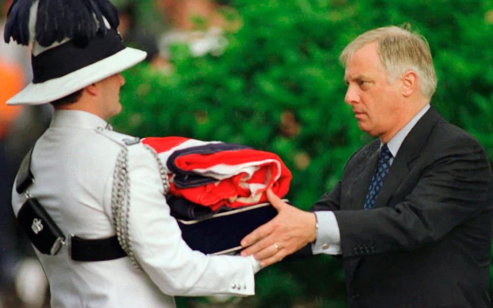 Then Governor Chris Patten, right, receives a folded British flag after its lowering at Government House in Hong Kong on June 30, 1997 as the British colony reverts to Chinese rule at midnight - AP/Eric Draper