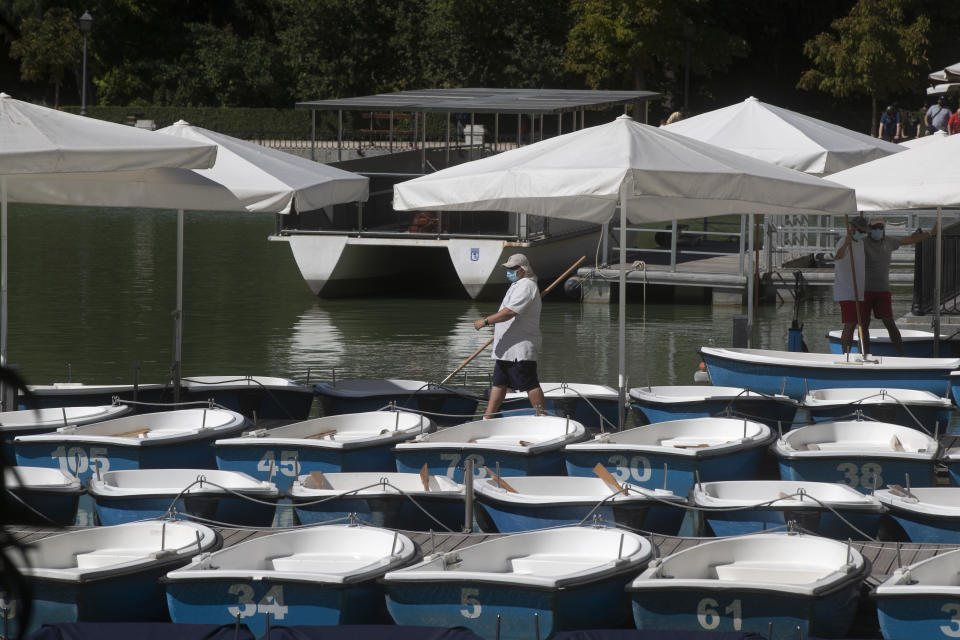 A worker prepares pleasure boats to be rented in the Retiro park, Madrid, Spain, Sunday, Aug. 23, 2020. Spain's top pandemic expert, Fernando Simon, has warned this week that "things are not going well" regarding the increase of infections that the country is seeing. (AP Photo/Paul White)