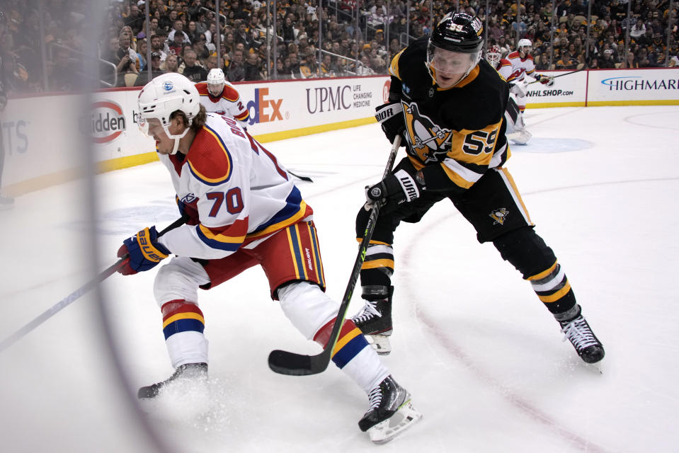 Pittsburgh Penguins' Jake Guentzel (59) loses the puck to New Jersey Devils' Jesper Boqvist (70) during the second period of an NHL hockey game in Pittsburgh, Friday, Dec. 30, 2022. (AP Photo/Gene J. Puskar)