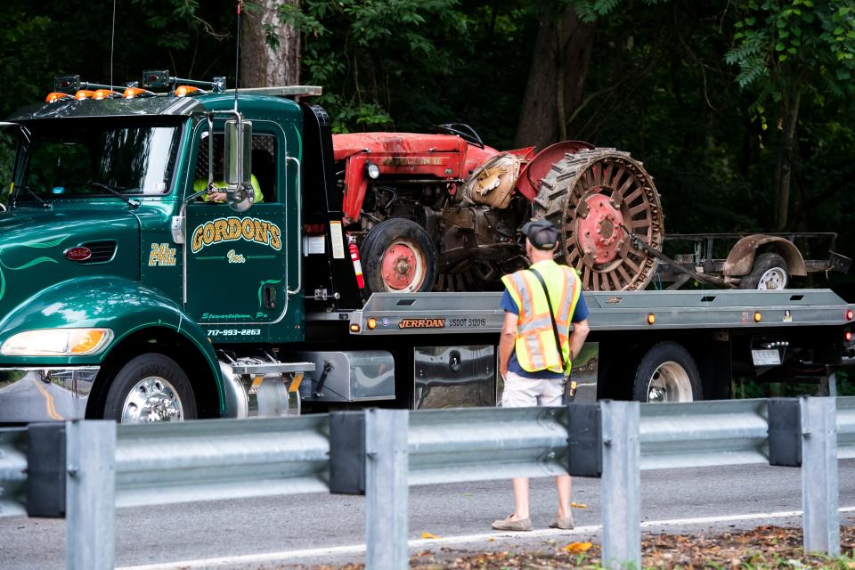 A flatbed tow truck removes a Massey Ferguson 65 tractor from the 1100 block of Furnace Road in Lower Chanceford Township on Friday, July 29, 2022, after a crash that left four dead and nine others transported to hospitals.