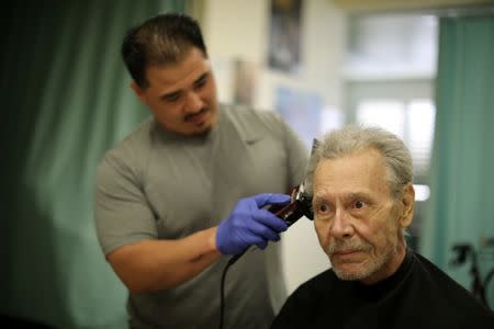 Pastoral Care Services Worker and inmate Kao Saephanh gives a haircut to Eddie Van Houton, 71, who has cancer, in the hospice at the California Medical Facility prison in Vacaville, California, U.S., May 23, 2018. REUTERS/Lucy Nicholson