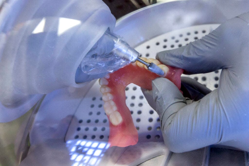 FILE – In this June 13, 2019, file photo a dentist smooths out the edges of new 3D printed dentures in Huntsville, Texas. (Brett Coomer/Houston Chronicle via AP, File)