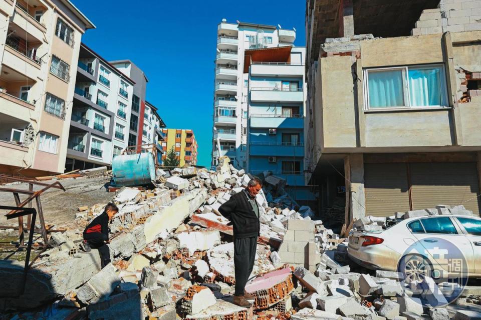 面臨家園遭強震摧毀，災民站在碎磚廢瓦上神情茫然。
