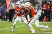 Miami quarterback Jake Garcia, left, hands off to running back Henry Parrish Jr. during the first half of an NCAA college football game against Pittsburgh, Saturday, Nov. 26, 2022, in Miami Gardens, Fla. (AP Photo/Lynne Sladky)