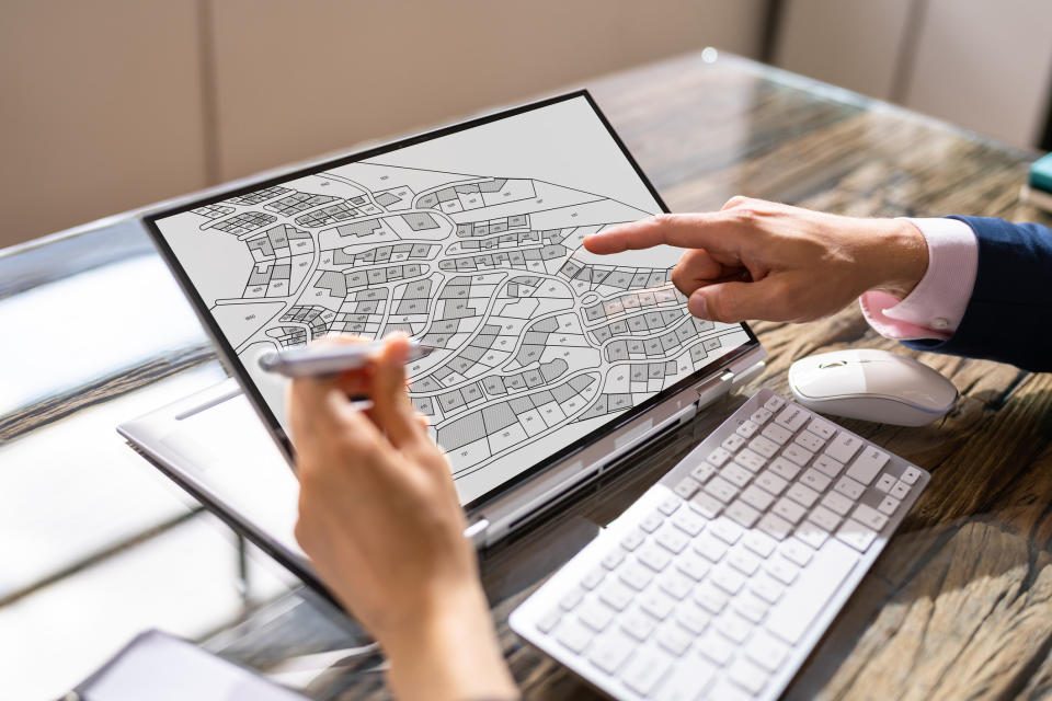 fingers pointing to a tablet with a neighborhood map on the screen