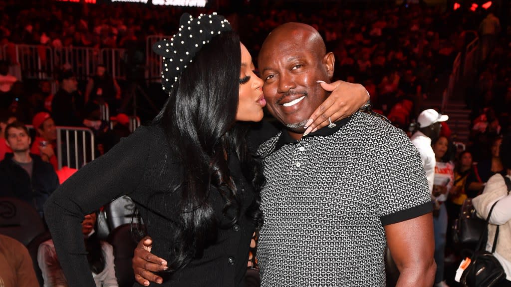 Porsha Williams in a black outfit kissing Simon Guobadia on the cheek; they're posing together at a basketball game