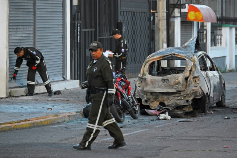 Des policiers inspectent l'épave d'un véhicule après l'explosion de deux voitures piégées à Quito, le 31 août 2023 en Equateur (Rodrigo BUENDIA)