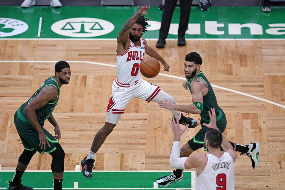 Chicago Bulls guard Coby White, center, passes the ball to Nikola Vucevic (9) while pressured by Boston Celtics forward Jayson Tatum, right, and center Tristan Thompson, left, during the first half of an NBA basketball game, Monday, April 19, 2021, in Boston. (AP Photo/Charles Krupa)