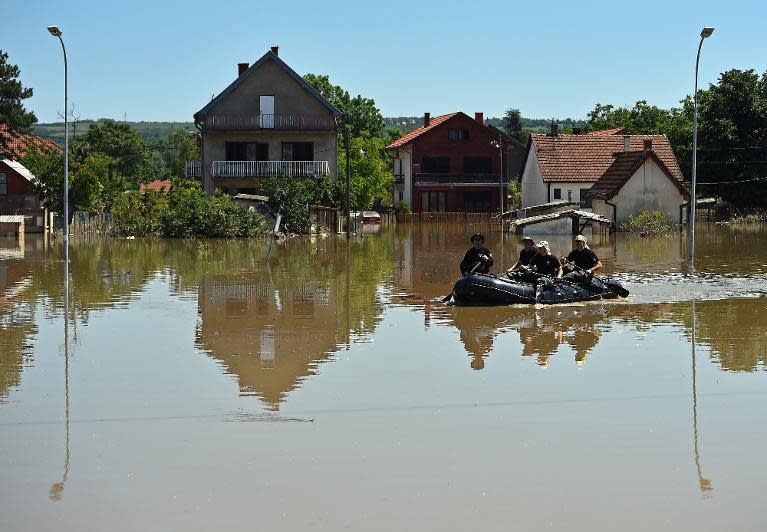 Serbian and Croatian rescuers paddle an inflatable boat on a flooded street of Obrenovac, 40 kilometers west of Belgrade, on May 22, 2014