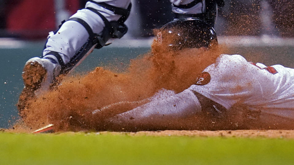 Boston Red Sox's Alex Verdugo gets a face full of dirt while sliding home safely on a single by Trevor Story during the sixth inning of the team's baseball game against the Seattle Mariners at Fenway Park, Thursday, May 19, 2022, in Boston. (AP Photo/Charles Krupa)