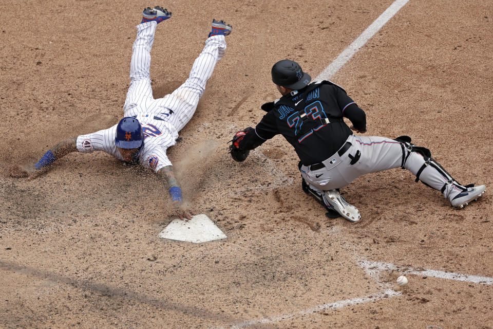 New York Mets' Javier Baez scores the game winning run past Miami Marlins catcher Alex Jackson during the ninth inning of the first game of a baseball doubleheader that started April 11 and was suspended because of rain, Tuesday, Aug. 31, 2021, in New York. The Mets won 6-5. (AP Photo/Adam Hunger)