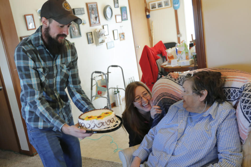 In this Friday, March 13, 2020 photo, Nic Talbott, left, hands a birthday cake to his grandmother, Rhoda Dineen, as he celebrates her 73rd birthday with his mother, Tracy Carlton, center, at his grandmother's home in Lisbon, Ohio. Talbott is a plaintiff in one of four lawsuits filed in federal courts challenging a Trump administration policy barring transgender Americans from enlisting in the military. (AP Photo/Keith Srakocic)