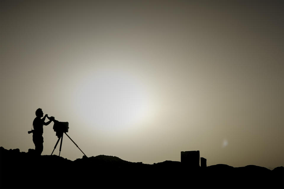 Rodrigo Abd, fotógrafo de The Associated Press, capta una imagen con una cámara de caja de madera en una antigua base de Estados Unidos, el 11 de junio de 2023, en el Valle de Arghandab, Afganistán. La cámara instantánea es una caja hecha a mano sobre un tripié que combina una cámara sencilla y un cuarto oscuro en uno. (AP Foto/Bram Janssen)