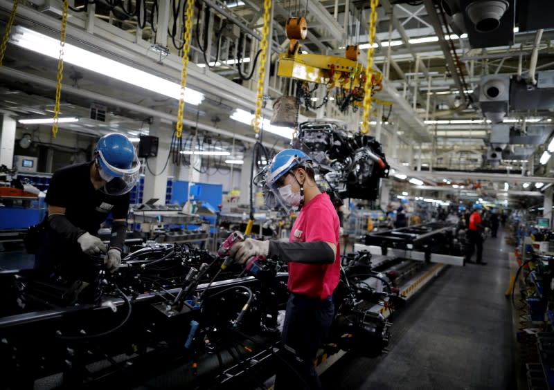 FILE PHOTO: Employees wearing protective face masks and face guards work on the automobile assembly line during the outbreak of the coronavirus disease (COVID-19) at the factory of Mitsubishi Fuso Truck and Bus Corp. in Kawasaki