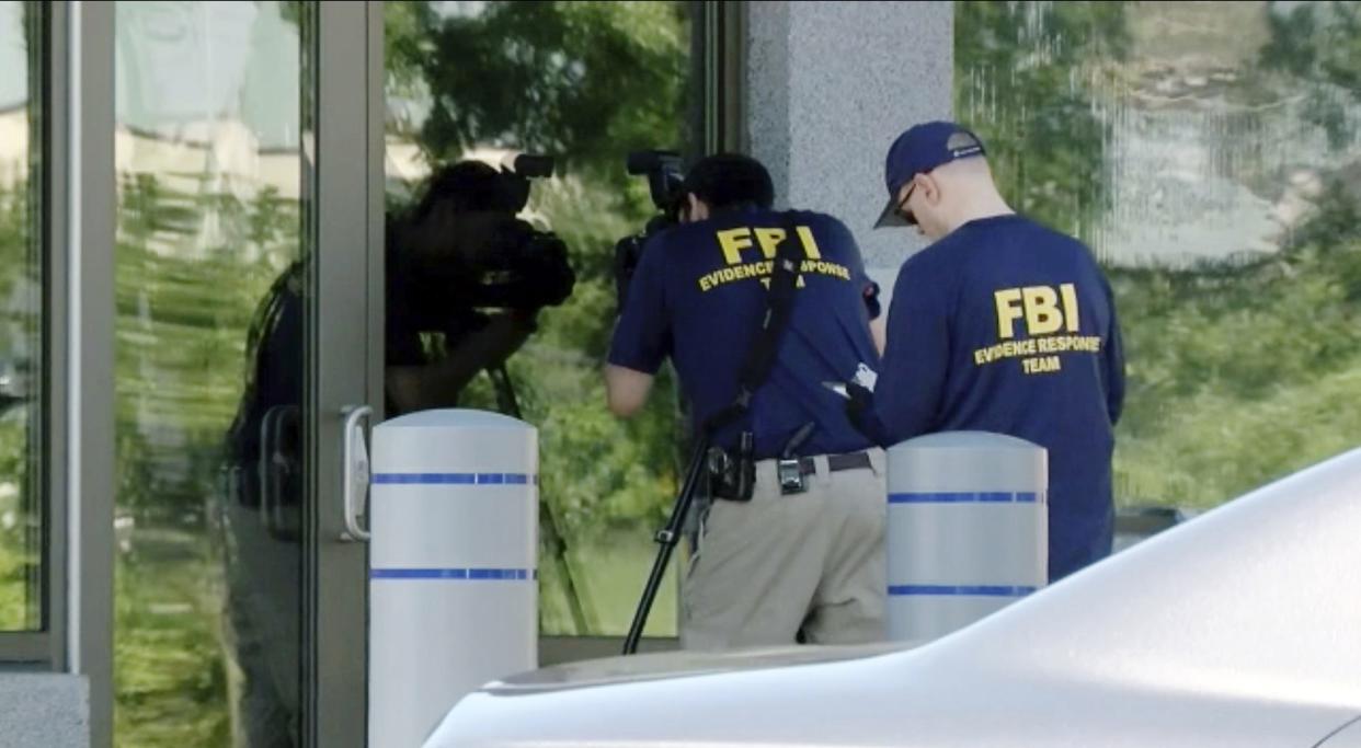 In this still image taken from WKEF/WRGT video, members of the FBI Evidence Response Team work outside the FBI building in Kenwood, Ohio, on Thursday.