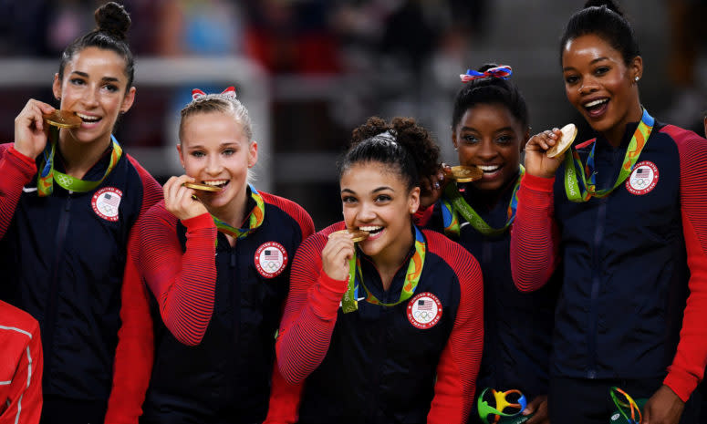 The United States women's olympic gymnastic team biting their gold medals.