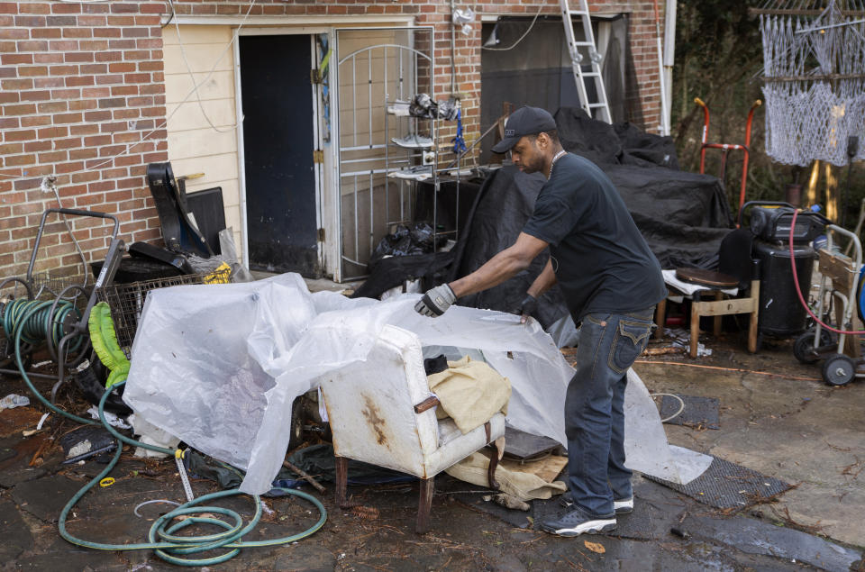 Prince Beatty covers up some chairs with a clear plastic cover to keep from getting wet on Monday, Jan. 10, 2022, in East Point, Ga. Beatty, a 47-year-old Navy veteran, faces eviction this month for unpaid rent despite his landlord getting more than $20,000 in federal rental assistance. (AP Photo/Hakim Wright Sr.)