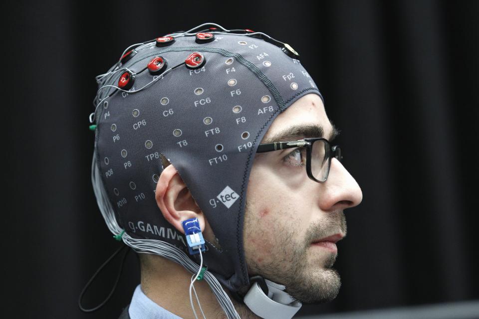 FILE - In this Feb. 17, 2011 file photo, a man sends brain-computer interface commands to a robotic computer during Science Conference at Convention Center in Washington. JWT, the global advertising and marketing company, predicts brain-computer interfaces, or BCIs, will push further into the commercial mainstream next year. (AP Photo/Jose Luis Magana, File)