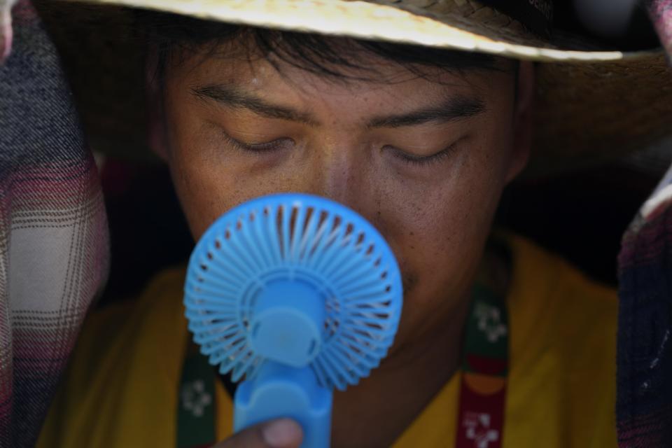 FILE - A World Youth Day volunteer uses a small fan to cool off from the intense heat, as he waits ahead of the Pope Francis arrival at Passeio Marítimo in Algés, just outside Lisbon, Aug. 6, 2023. The European climate agency calculates that November, for the sixth month in a row, the globe set a new monthly record for heat, adding the hottest autumn to the broken records of record-breaking heat this year. (AP Photo/Armando Franca, File)