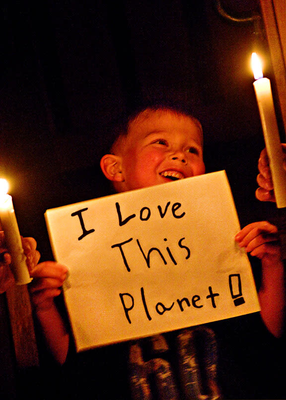 A young boy holding up a handmade sign reading