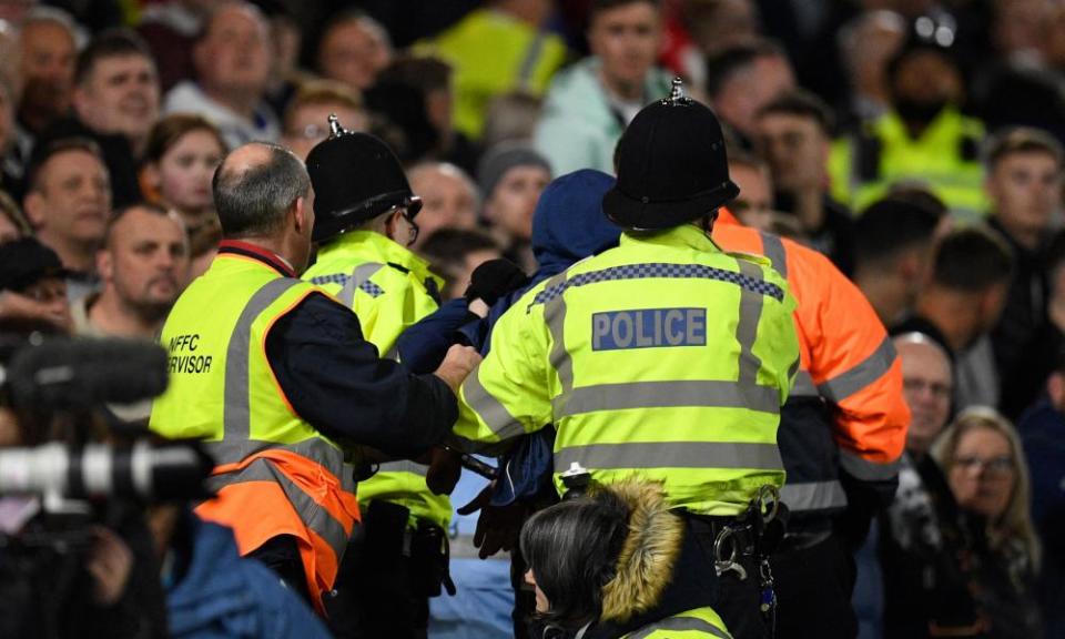 La policía saca a miembros de la multitud en un partido de fútbol