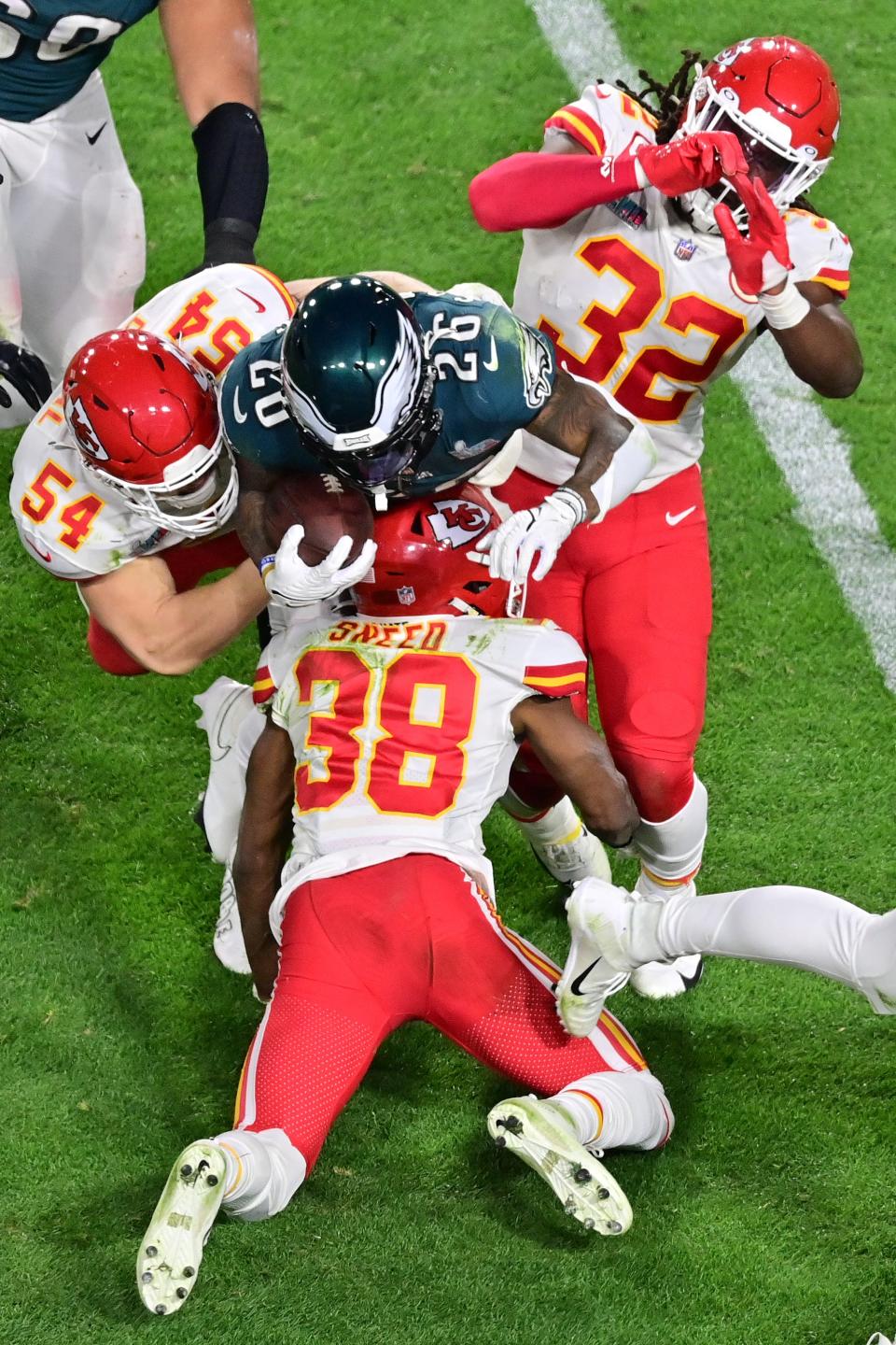 Philadelphia Eagles running back Miles Sanders (26) is tackled by Kansas City Chiefs linebacker Nick Bolton (32) and cornerback L'Jarius Sneed (38) and linebacker Leo Chenal (54) during the third quarter of Super Bowl LVII at State Farm Stadium.