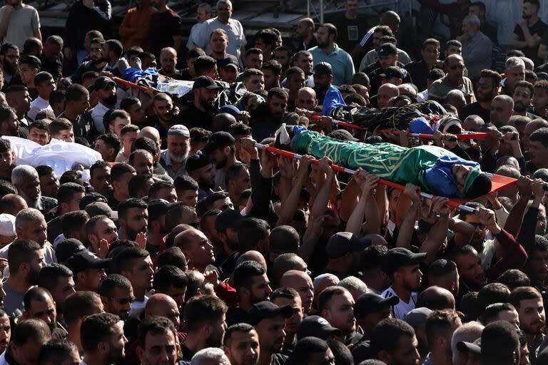 Los dolientes cargan los cuerpos de los hombres palestinos muertos en una incursión israelí en el campo de Nur Shams para refugiados palestinos en la ocupada Cisjordania, durante su procesión fúnebre el 21 de abril de 2024.