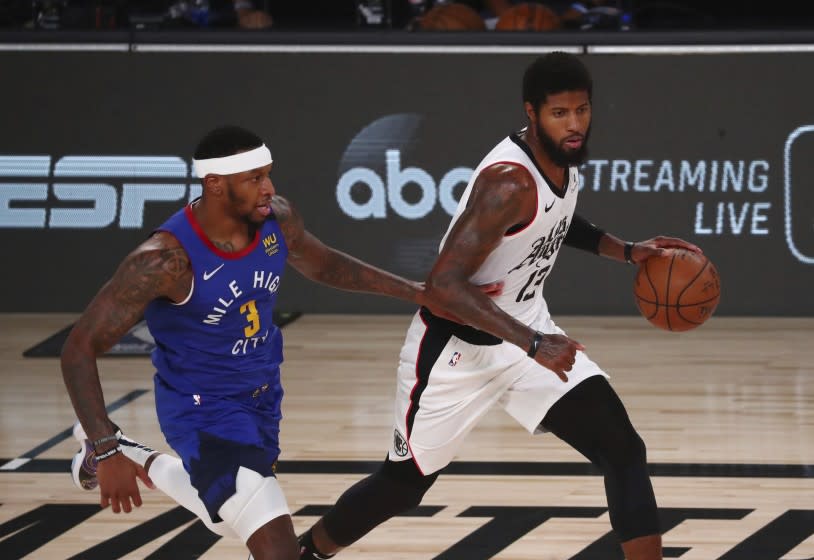 Los Angeles Clippers' guard Paul George (13) controls the ball while defended by Denver Nuggets forward Torrey Craig (3) during the first half of an NBA basketball game Wednesday, Aug. 12, 2020, in Lake Buena Vista, Fla. (Kim Klement/Pool Photo via AP)