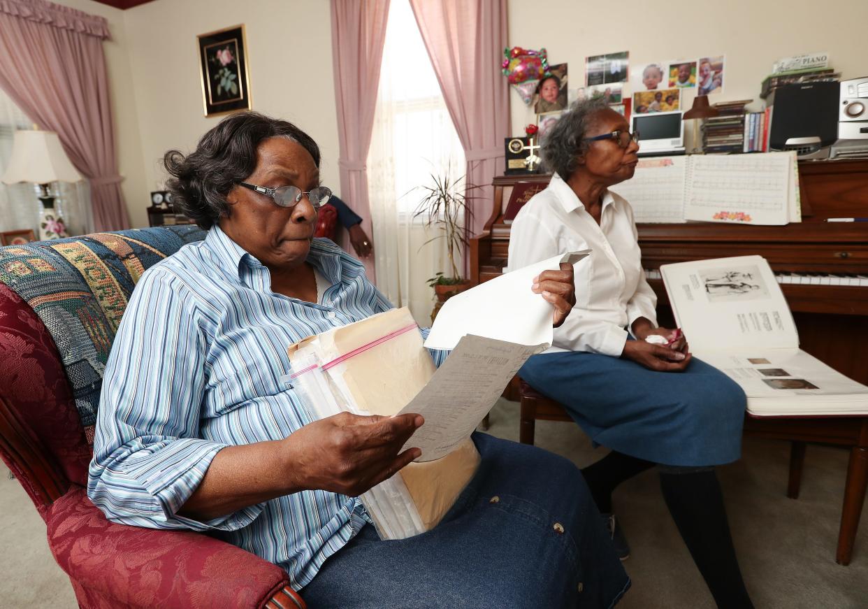 Ruth Johnson-Watts, 81, left, looks through historical documents as her sister Gladys Johnson Dorsey, 73, visits with her at Johnson-Watts' home in Cincinnati on March 20, 2024. They are descendants of Oliver Lewis, the first jockey to win the Kentucky Derby, in 1875.