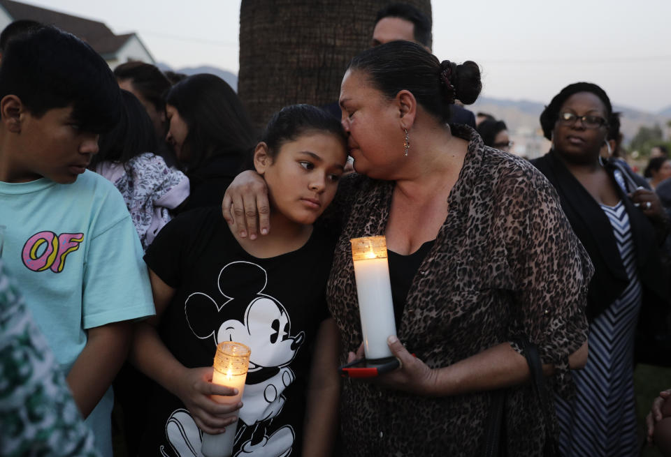 Betty Rodríguez, derecha, conforta a su nieta Giselle durante un servicio de oraciones en honor a las víctimas del tiroteo la víspera en la escuela primaria North Park en San Bernardino, California, el martes, 11 de abril del 2017. (AP Foto/Jae C. Hong)