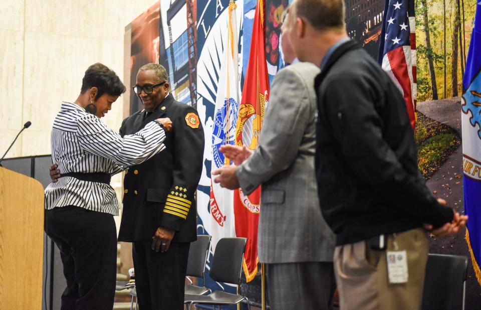 Tamra Sturdivant, wife of Lansing Fire Department Chief Brian Sturdivant pins on her husband's badge after he was sworn in, Wednesday, June 8, 2022, at Lansing City Hall.  Looking on are City Clerk Chris Swope, and Mayor Andy Schor.