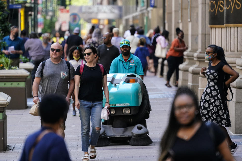 People, some without masks, walk along Market Street in Philadelphia, Friday, May 21, 2021. (AP Photo/Matt Rourke)