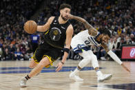 Golden State Warriors guard Klay Thompson (11) works towards the basket while defended by Minnesota Timberwolves guard D'Angelo Russell (0) during the second half of an NBA basketball game, Wednesday, Feb. 1, 2023, in Minneapolis. (AP Photo/Abbie Parr)