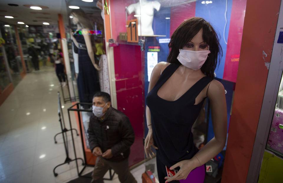 A mannequin wearing a face mask stands at the entrance of a women's clothing store in La Paz, Bolivia, Monday, June 1, 2020. After more than two months of quarantine to curb the spread of the new coronavirus the government authorized the restart of public transport and several industrial and commercial activities. (AP Photo/Juan Karita)