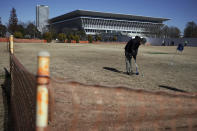 A man wearing a protective mask to help curb the spread of the coronavirus plays ground golf near the Tokyo Aquatics Center, one of the venues of Tokyo 2020 Olympic and Paralympic games, in Tokyo Wednesday, Jan. 20, 2021. The postponed Tokyo Olympics are to open in just six months. Local organizers and the International Olympic Committee say they will go ahead on July 23. But it’s still unclear how this will happen with virus cases surging in Tokyo and elsewhere around the globe. (AP Photo/Eugene Hoshiko)