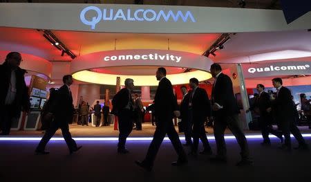 Visitors walk past the Qualcomm stand at the Mobile World Congress in Barcelona, February 24, 2014. REUTERS/Albert Gea