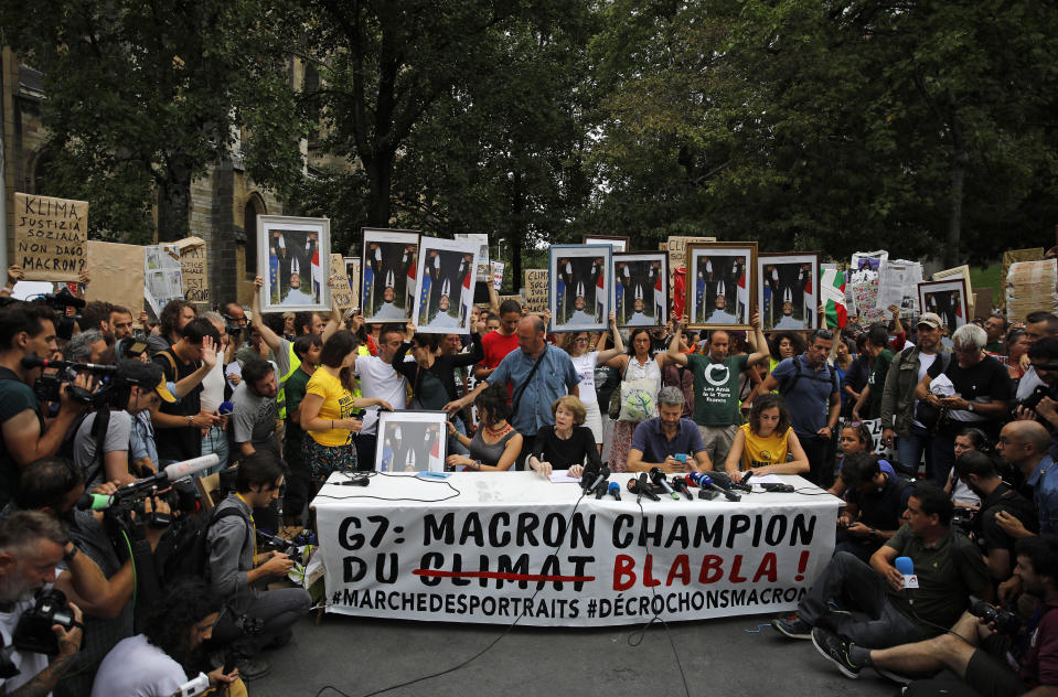 Demonstrators hold up upside down portraits of French President Emmanuel Macron during a protest in Bayonne, France Sunday, Aug. 25, 2019. Critics of French President Emmanuel Macron marched near the G-7 summit he is hosting to demand he do more to protect French workers and the planet. A melange of activists, some wearing yellow vests, carried portraits of Macron as they marched Sunday through the southwest city of Bayonne. Some held the portraits upside down. (AP Photo/Emilio Morenatti)