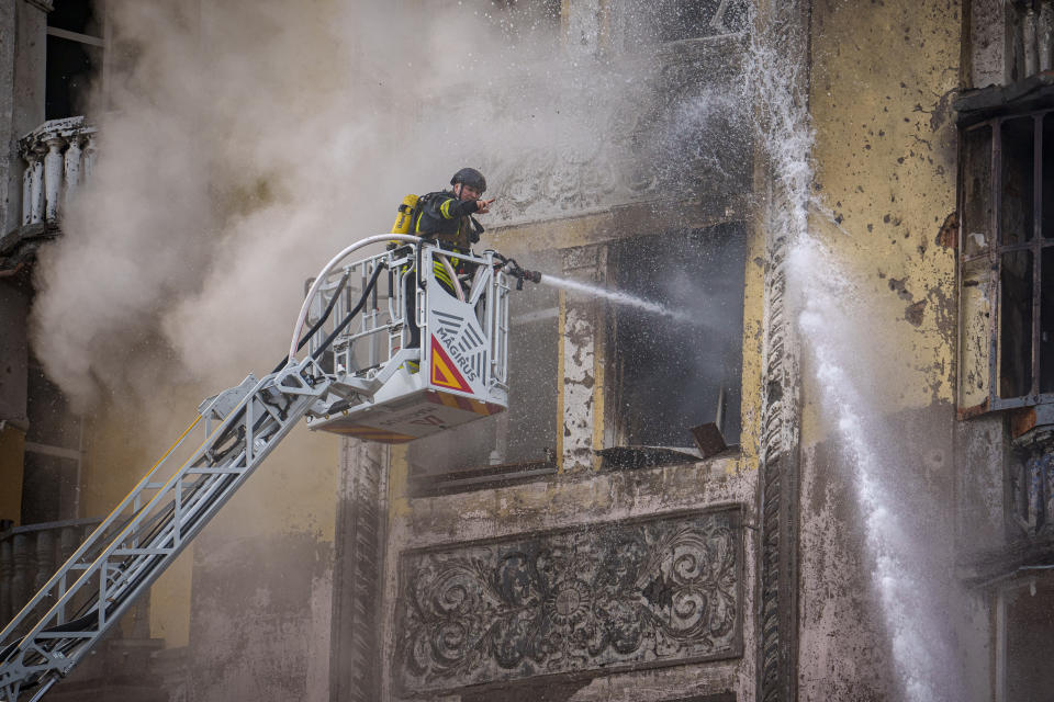 A firefighter gestures while spraying water inside a building at the site of a Russian attack, in Kyiv, Ukraine, Thursday, March 21, 2024. Around 30 cruise and ballistic missiles were shot down over Kyiv on Thursday morning, said Serhii Popko, the head of Kyiv City Administration. The missiles were entering Kyiv simultaneously from various directions in a first missile attack on the capital in six weeks. (AP Photo/Vadim Ghirda)