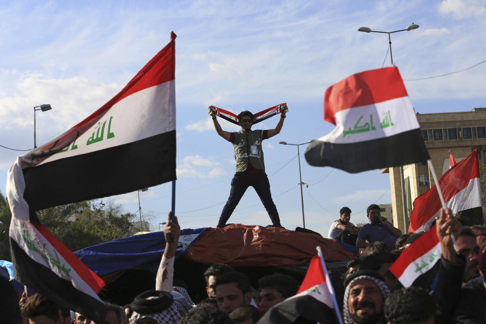 FILE - In this March 31, 2016 file photo, followers of Shiite cleric Muqtada al-Sadr wave national flags as they end their sit-in outside the heavily guarded Green Zone in Baghdad, Iraq. The zone has been a barometer for tension and conflict in Iraq for nearly two decades. The sealed-off area, with its palm trees and monuments, is home to the gigantic U.S. Embassy in Iraq, one of the largest diplomatic missions in the world. It has also been home to successive Iraqi governments and is off limits to most Iraqis. (AP Photo/Khalid Mohammed, File)