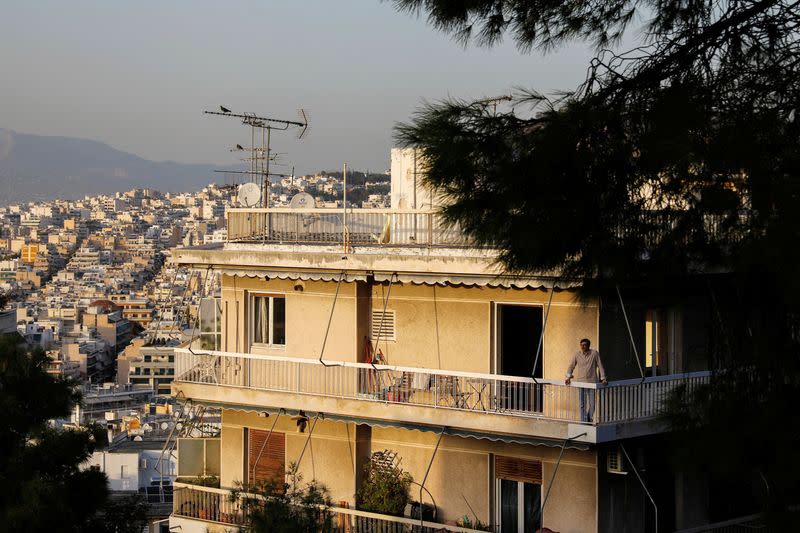 A man stands on a balcony, in Athens