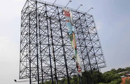 Workers fold a billboard sign in anticipation of strong winds brought by Typhoon Hagupit, locally named Ruby, on a coastal road in Cavite City, south of Manila December 4, 2014. REUTERS/Romeo Ranoco